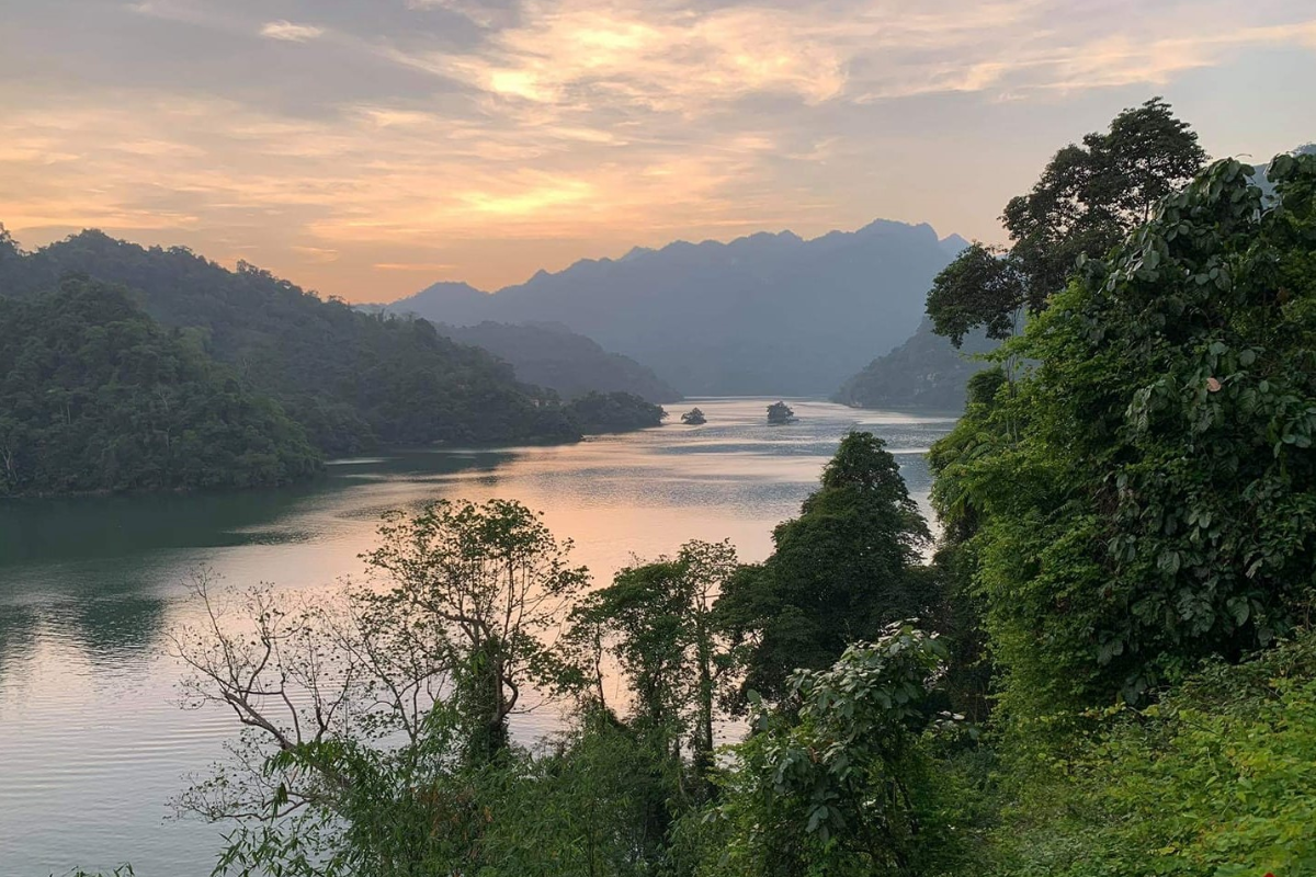 Ba Be Lake with calm waters reflecting mountains and sky at sunrise
